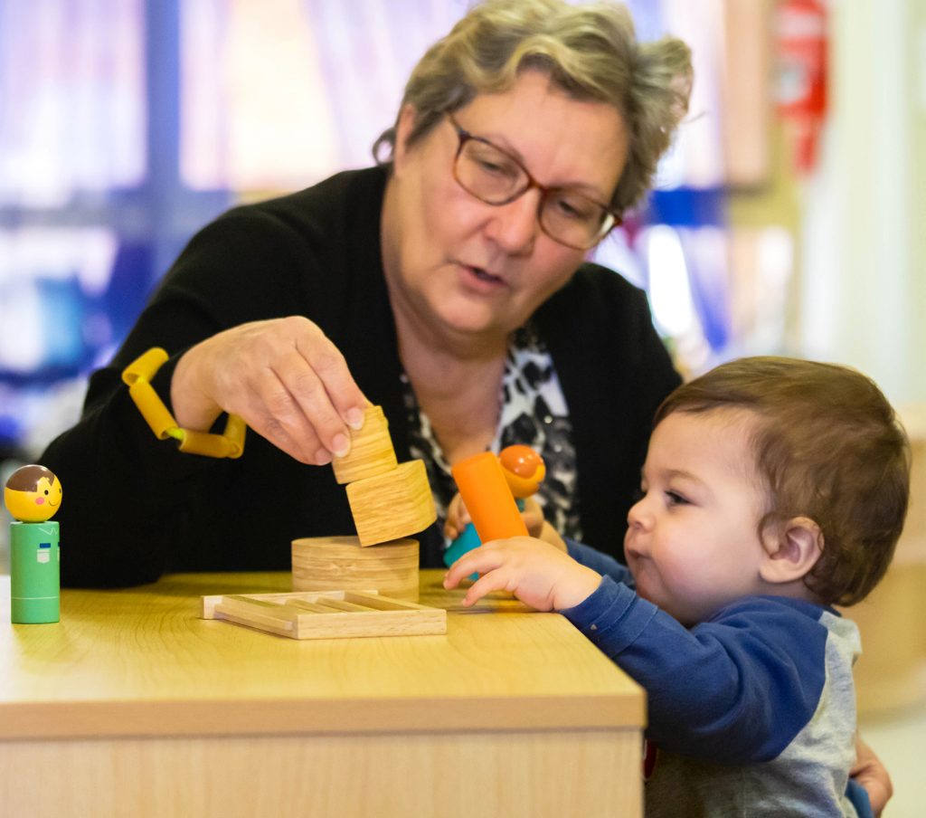Early childhood teacher showing playgroup child blocks