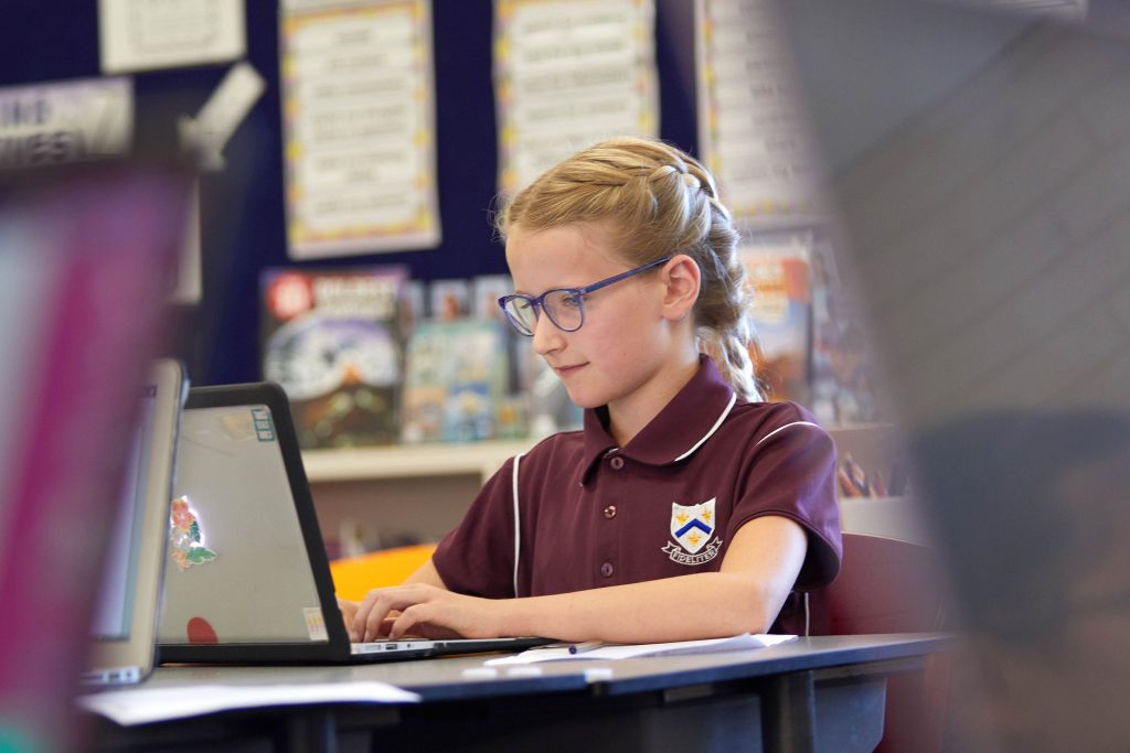 A young girl in glasses using a laptop at St Mary's Girl's boarding School, Early Learning Centre Years 3 to 6.