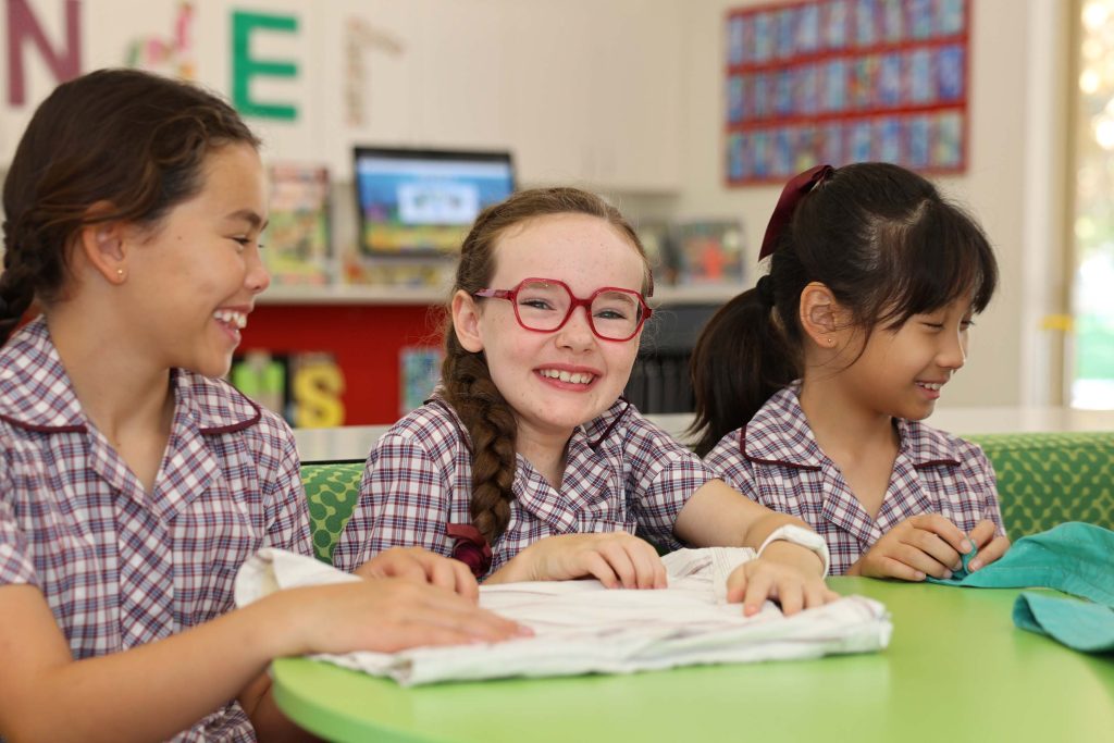 Three girls in school uniforms sitting at a table in our Early Learning Centre at St Mary's Girl's boarding School.