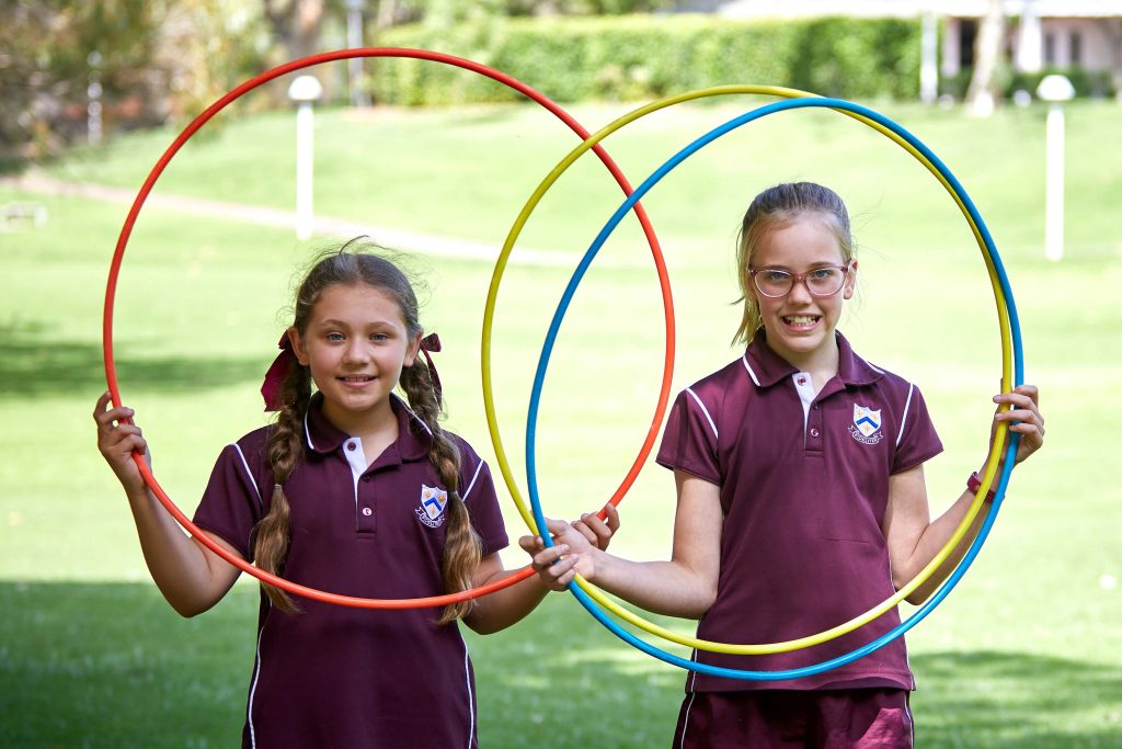 Two girls from St Mary's Girl's boarding School hold hula hoops in the grass.