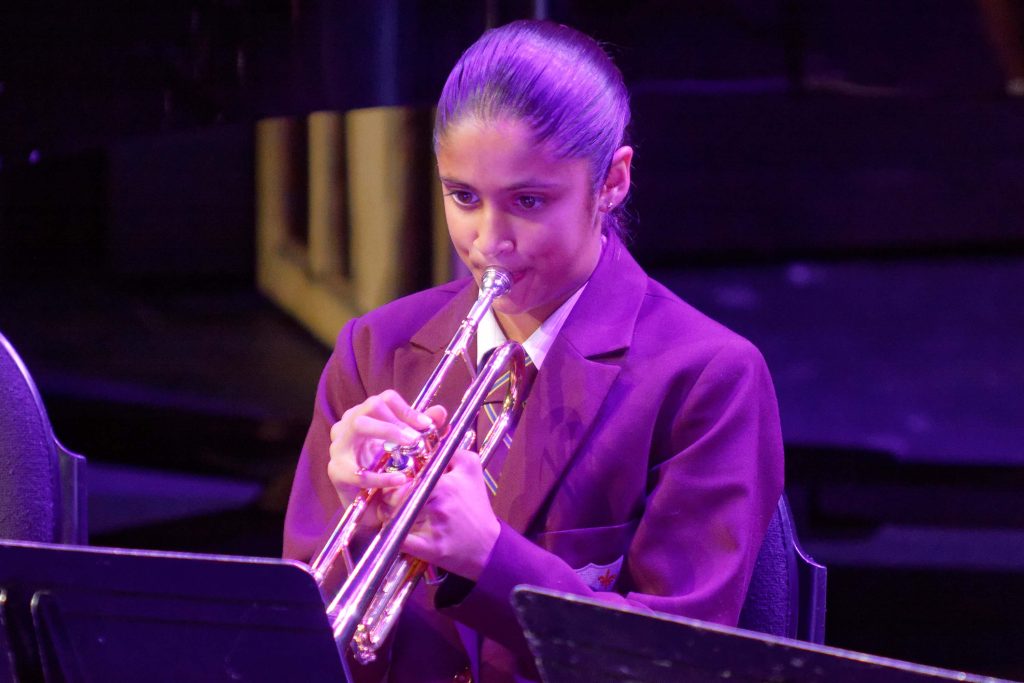 Image of a girl in a purple jacket showcasing her trumpet skills at Girls' Early Learning at St Mary's School.