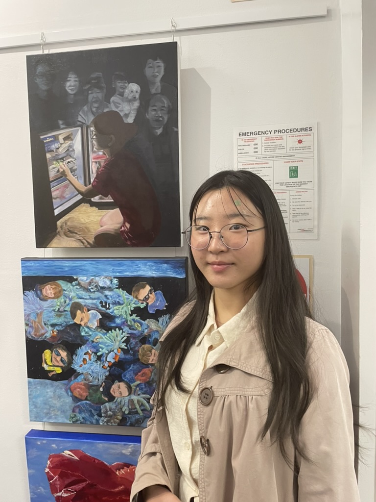 Erin posing in front of her winning artwork for the U18s category. 